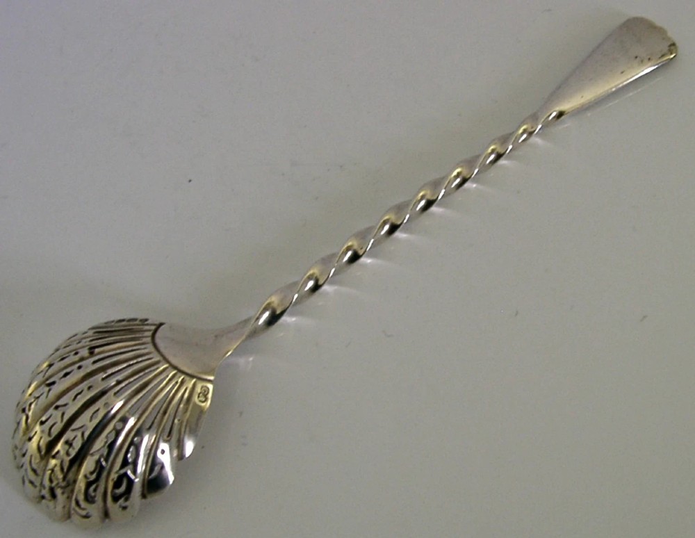 Victorian sterling silver sugar sifter spoon featuring a twisted stem, shell-shaped pierced bowl, and engraved heron crest handle terminal. View VI
