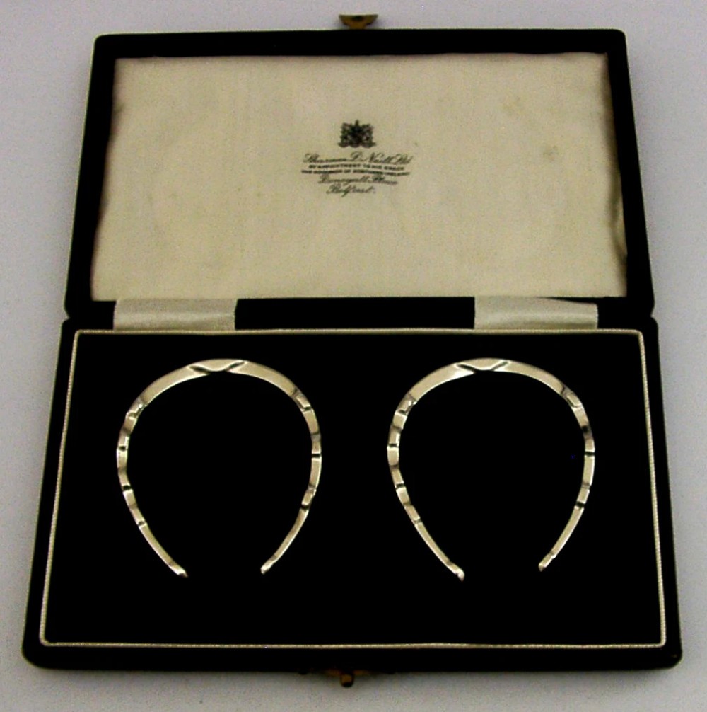 A set of two sterling silver horseshoe-shaped napkin rings presented inside a fitted black presentation case.