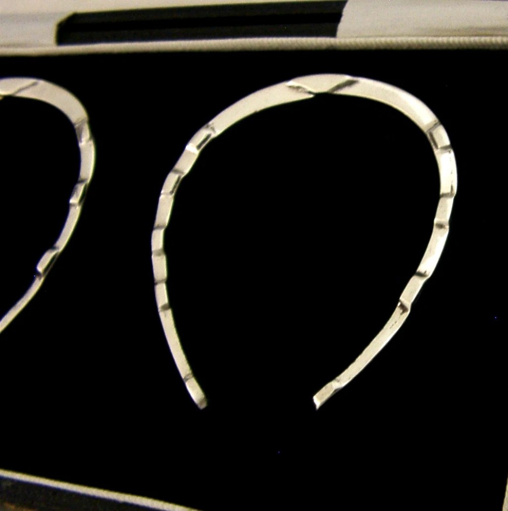 A set of two sterling silver horseshoe-shaped napkin rings presented inside a fitted black presentation case. View II