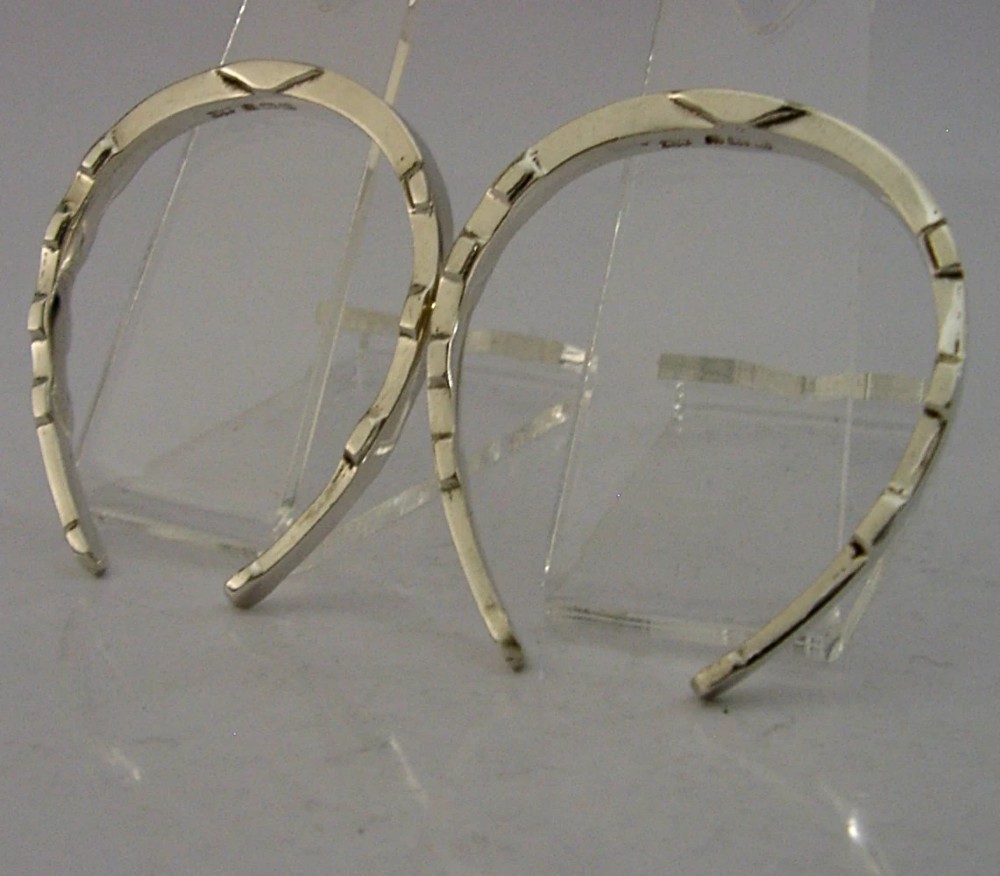 A set of two sterling silver horseshoe-shaped napkin rings presented inside a fitted black presentation case. View V