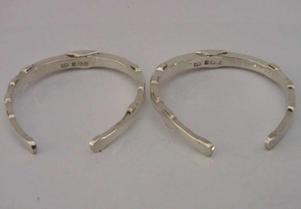 A set of two sterling silver horseshoe-shaped napkin rings presented inside a fitted black presentation case. View VII