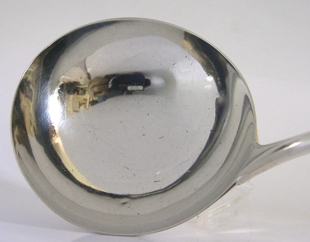 A Georgian sterling silver soup ladle featuring a rounded bowl, long handle, and engraved heraldic crest. View III