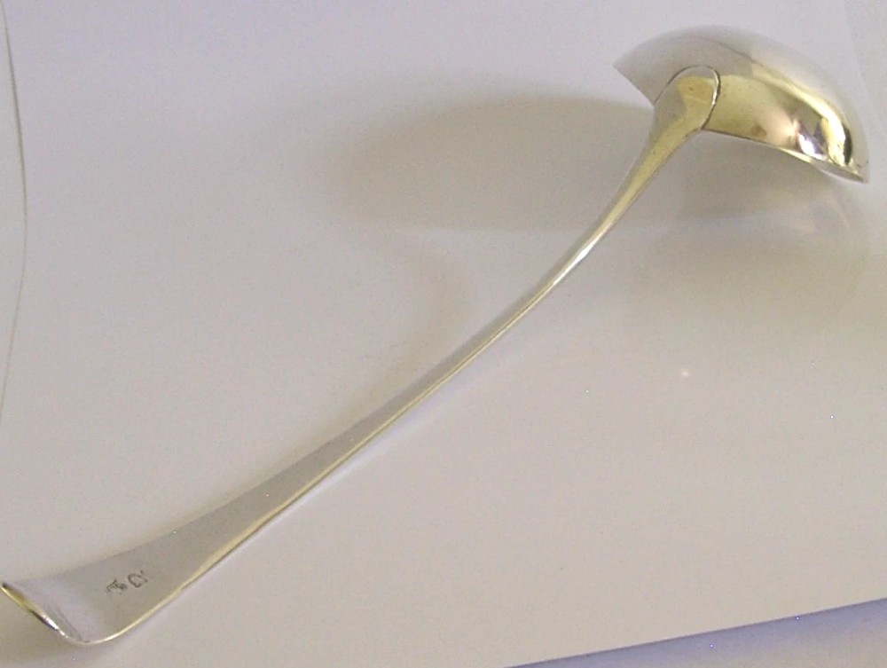 A Georgian sterling silver soup ladle featuring a rounded bowl, long handle, and engraved heraldic crest. View VI