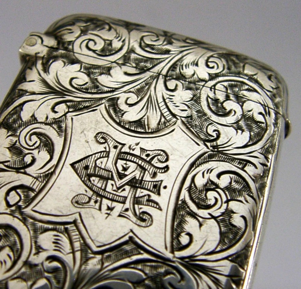 Victorian sterling silver vesta case decorated with hand-engraved foliate scrollwork and a central monogrammed shield cartouche. View II
