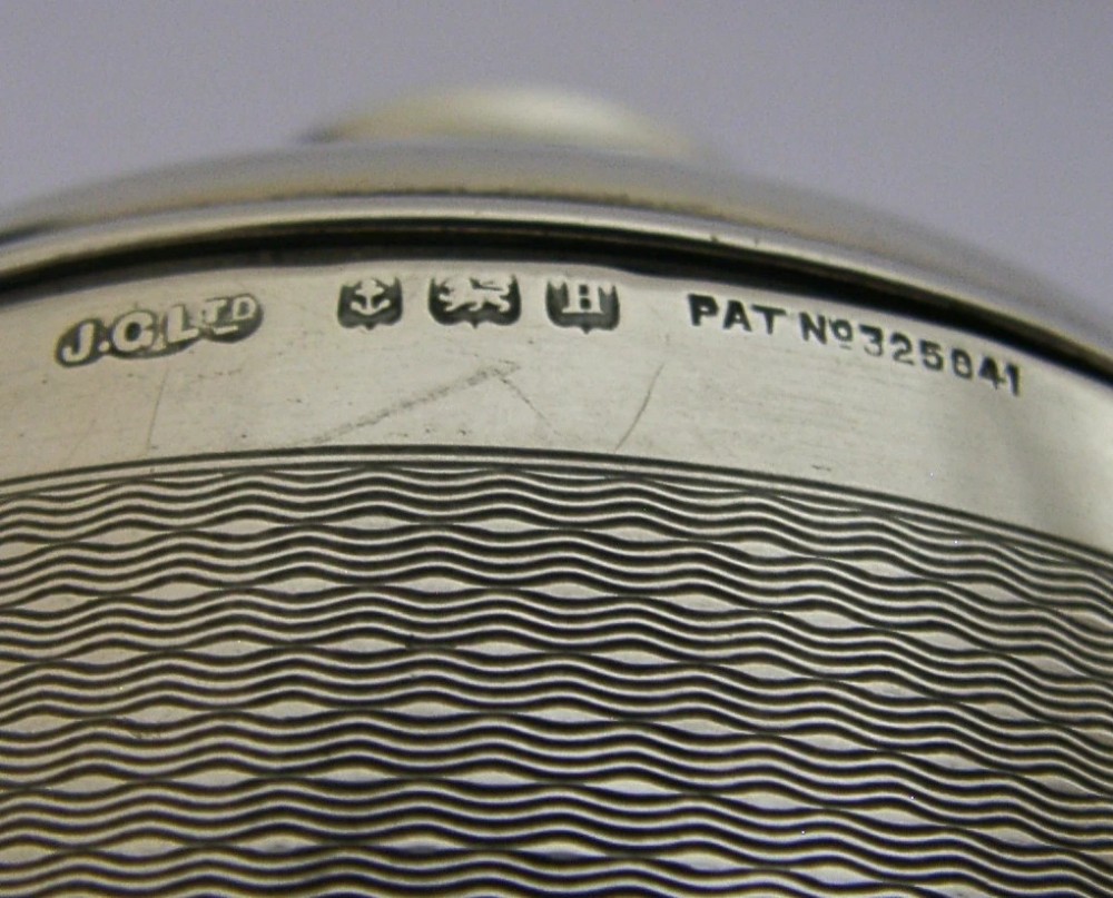A cylindrical Art Deco sterling silver cigarette dispenser featuring engine-turned patterning, a central polished silver band, and a round knob finial on top. View VIII