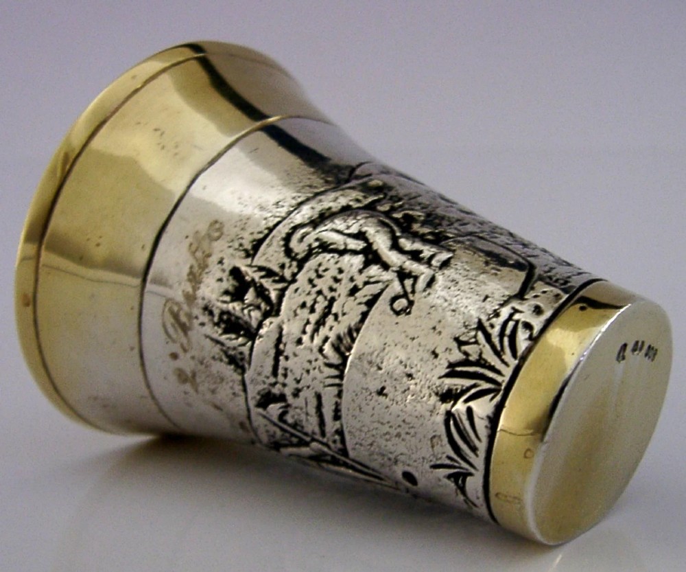 An antique 800 solid silver beaker with gilded rims featuring an embossed relief scene of a golfer.