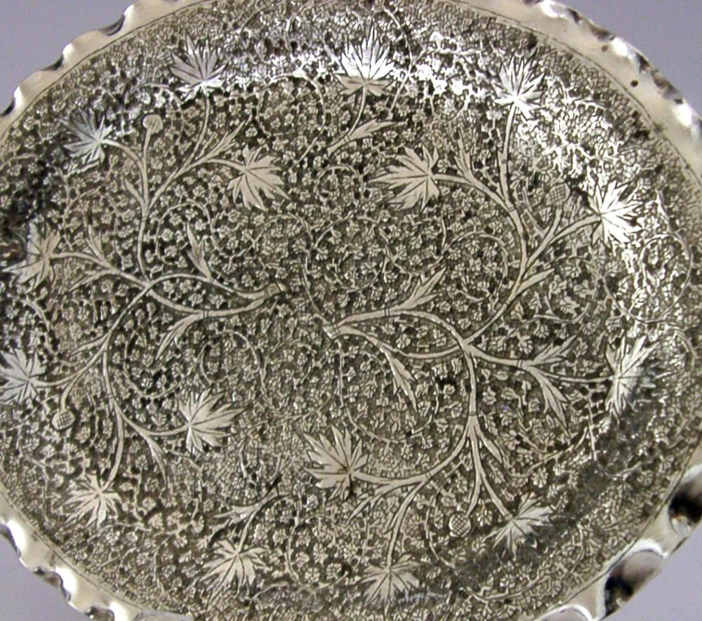 An oval solid silver dish featuring dense chased leaf patterns and a scalloped fluted border. View III