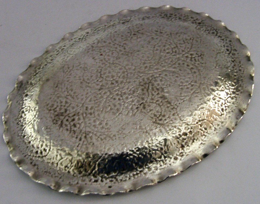 An oval solid silver dish featuring dense chased leaf patterns and a scalloped fluted border. View IV