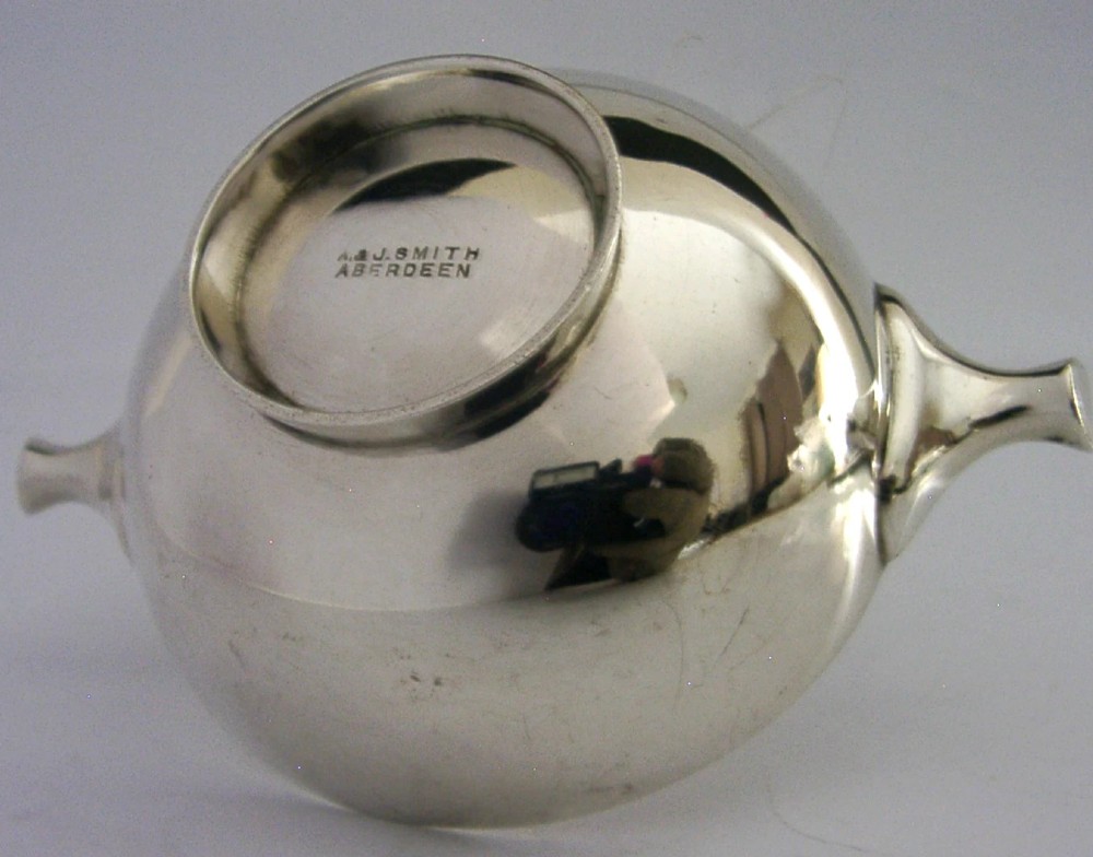 A polished sterling silver shallow drinking cup featuring two flat side handles and British hallmarks stamped on the exterior wall. View VI