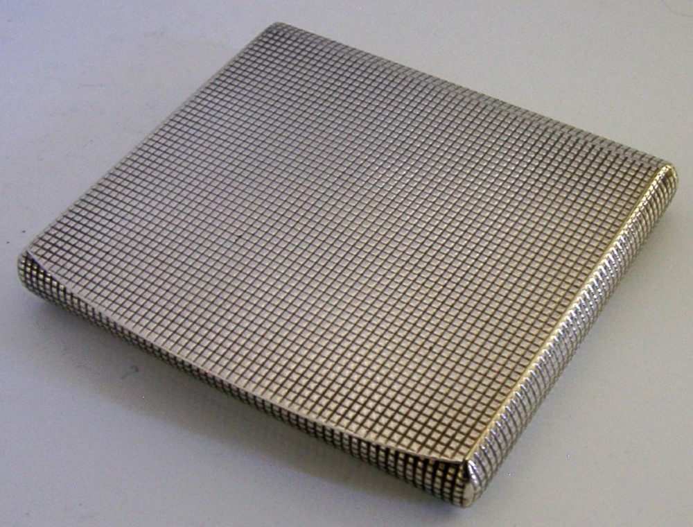 An open sterling silver case displaying an engine-turned grid pattern on the exterior and a gilt metallic interior. View VI