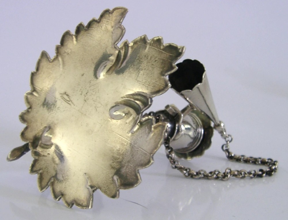An early Victorian sterling silver chamberstick featuring a shaped leaf base, a coiled vine handle, and an attached chain with a conical snuffer. View VIII