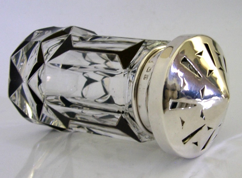 An Art Deco sugar caster featuring a faceted cut-glass body with black geometric enamel details and a pierced sterling silver top. View IV