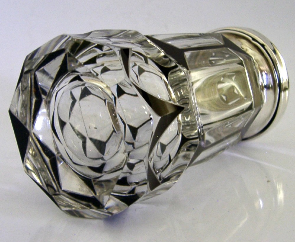 An Art Deco sugar caster featuring a faceted cut-glass body with black geometric enamel details and a pierced sterling silver top. View V