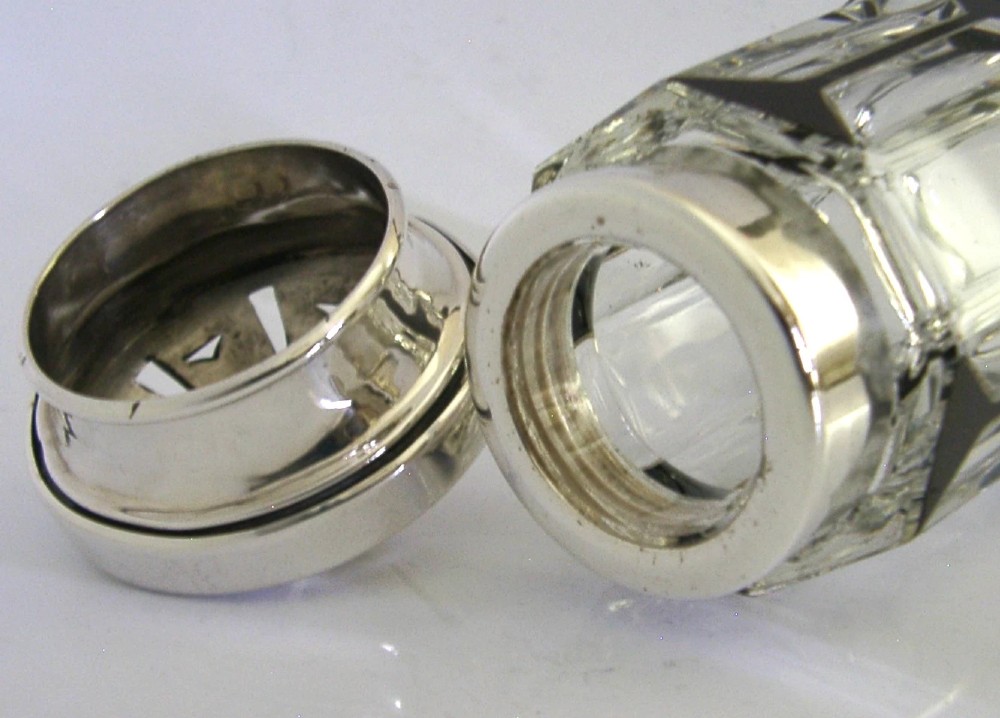 An Art Deco sugar caster featuring a faceted cut-glass body with black geometric enamel details and a pierced sterling silver top. View VI