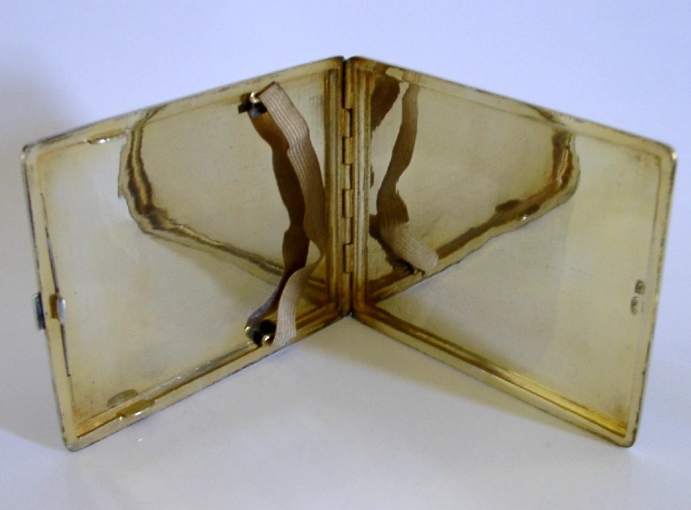 A rectangular solid silver cigarette case featuring dense hand-engraved bird and foliate patterns with a gold monogram in the upper corner. View VIII