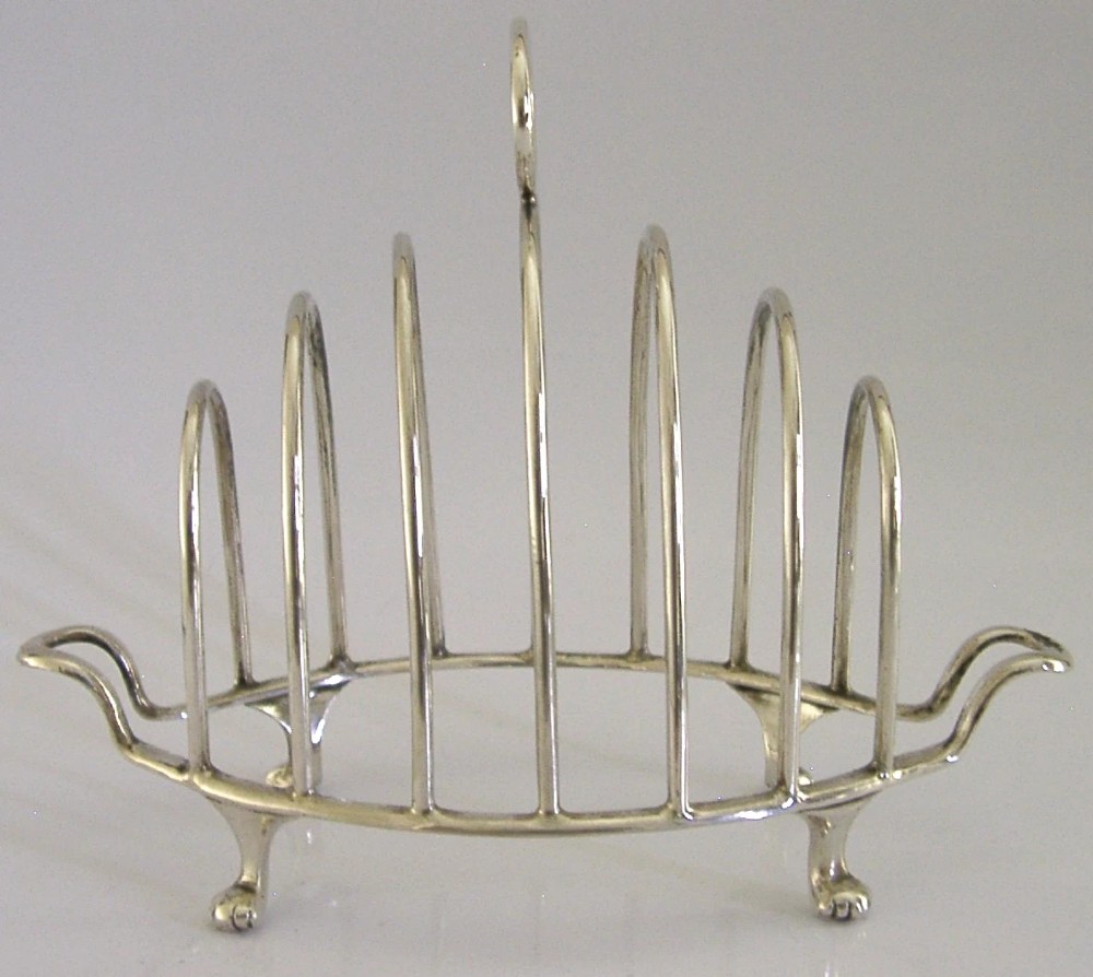A 1925 English sterling silver six-slice toast rack featuring arched wire dividers, a top ring handle, and small paw feet. View II
