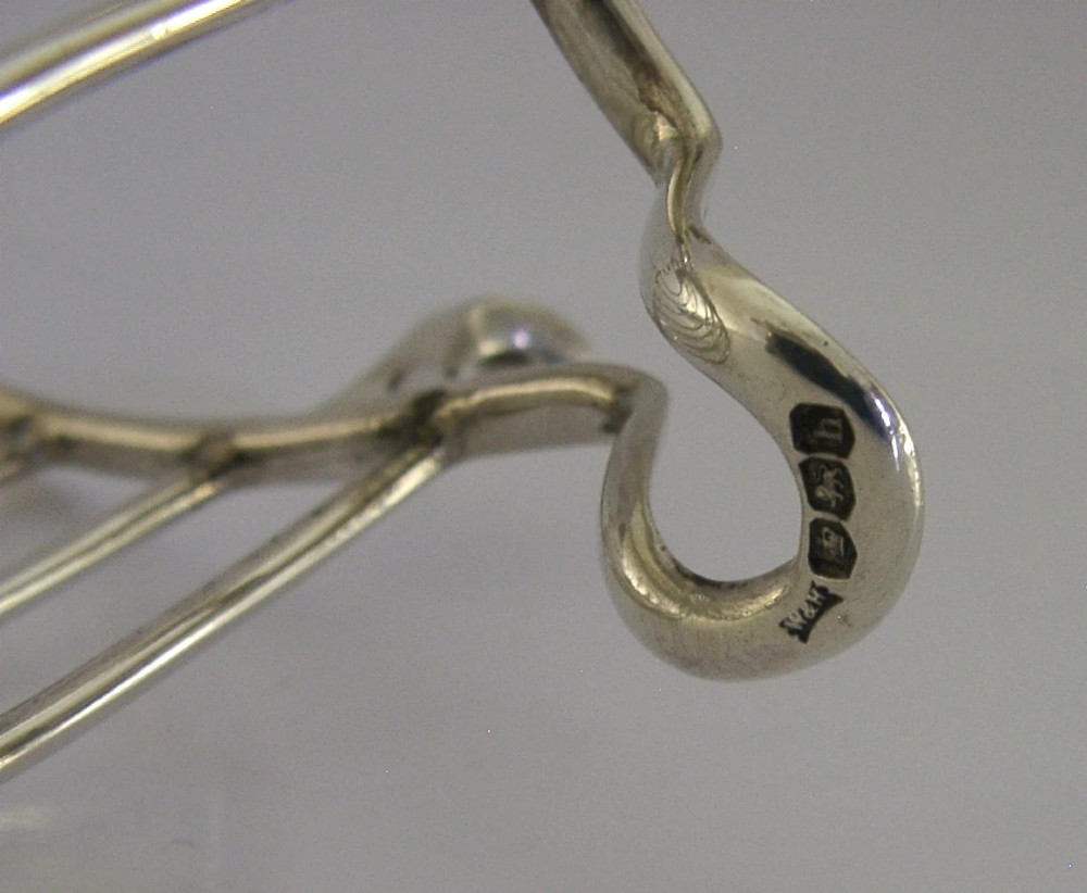 A 1925 English sterling silver six-slice toast rack featuring arched wire dividers, a top ring handle, and small paw feet. View VIII