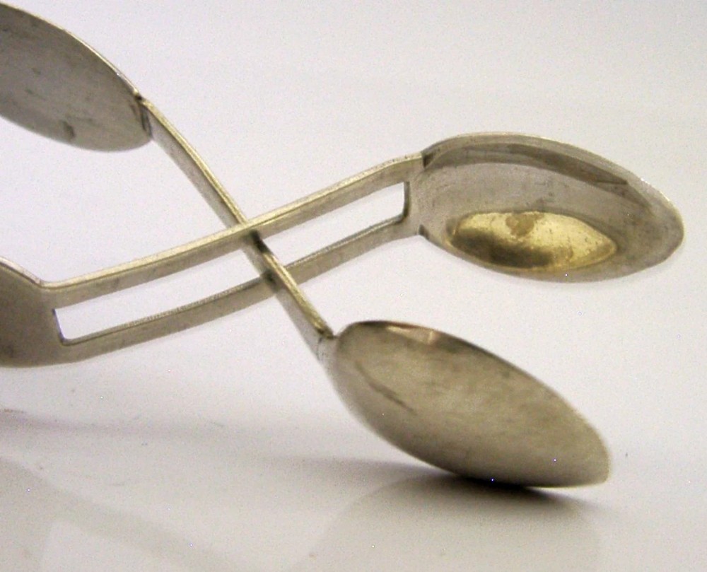 A pair of Edwardian sterling silver sugar tongs featuring smooth contoured arms and spoon-shaped grips. View II