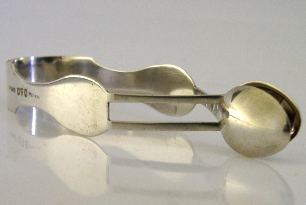 A pair of Edwardian sterling silver sugar tongs featuring smooth contoured arms and spoon-shaped grips. View III