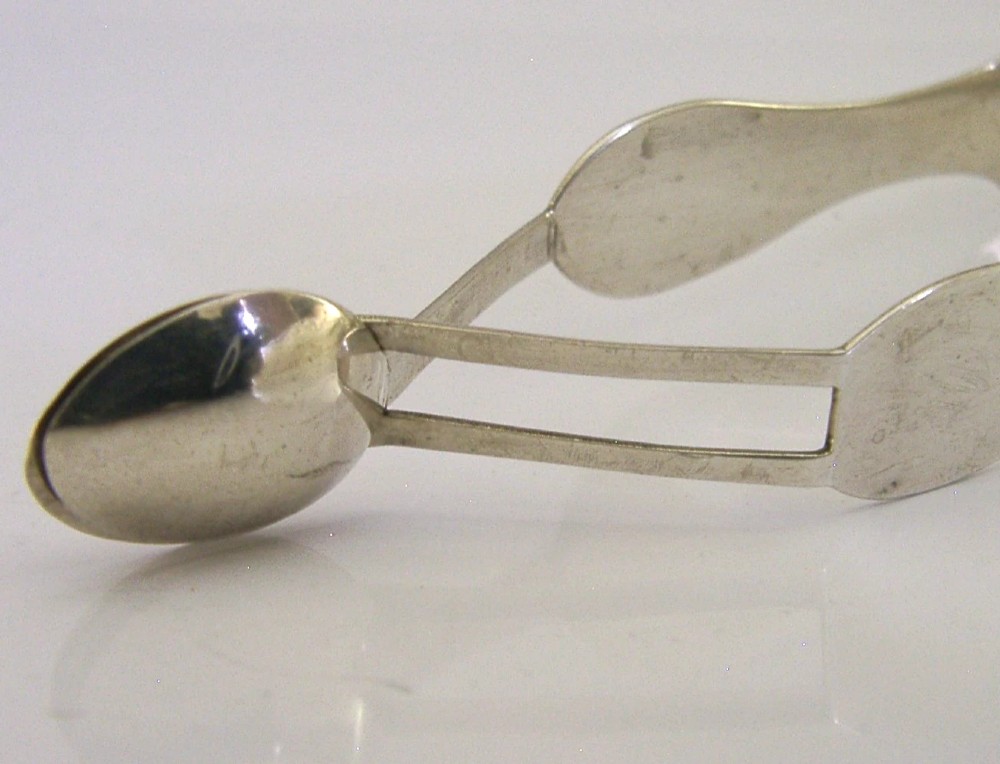 A pair of Edwardian sterling silver sugar tongs featuring smooth contoured arms and spoon-shaped grips. View IV
