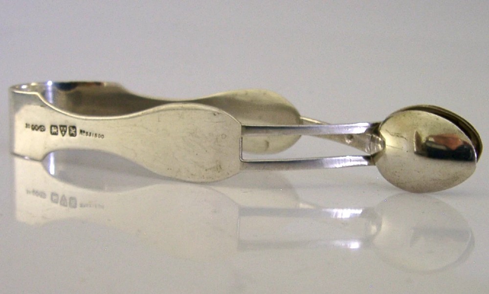 A pair of Edwardian sterling silver sugar tongs featuring smooth contoured arms and spoon-shaped grips. View V