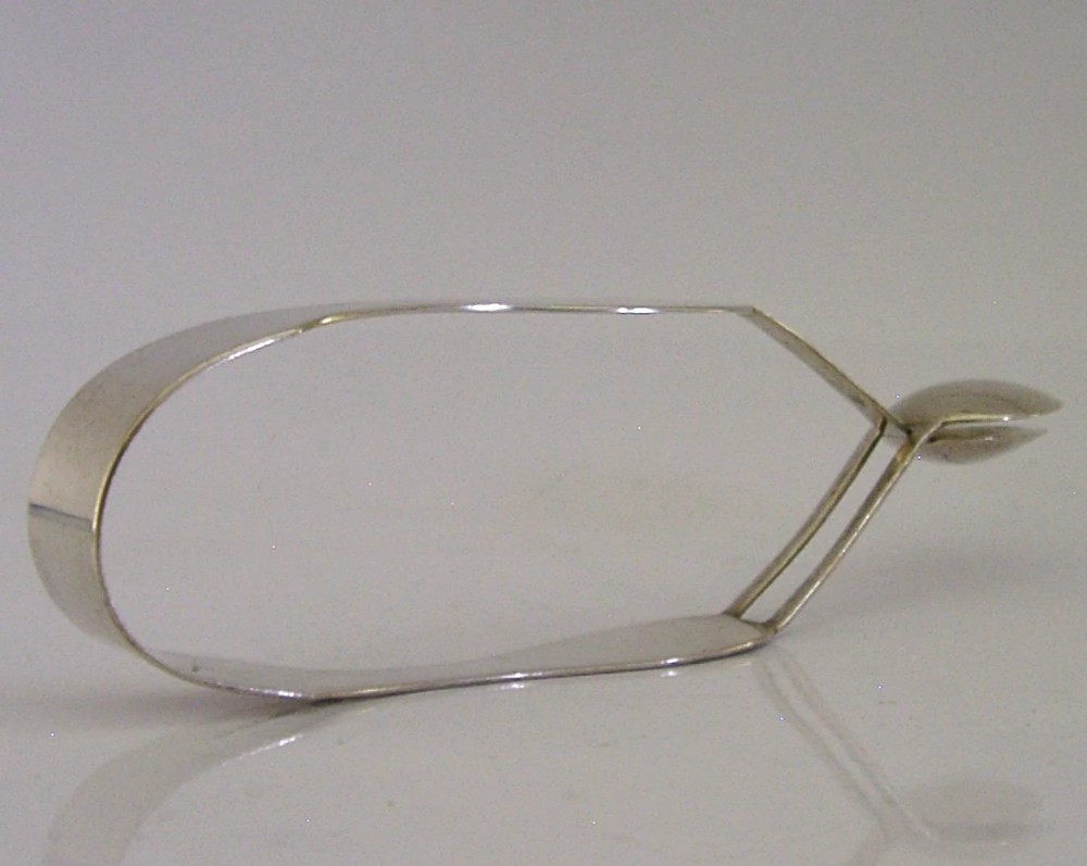 A pair of Edwardian sterling silver sugar tongs featuring smooth contoured arms and spoon-shaped grips. View VI