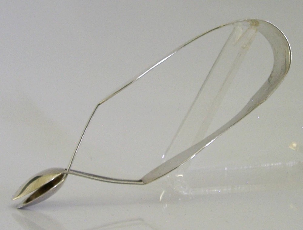 A pair of Edwardian sterling silver sugar tongs featuring smooth contoured arms and spoon-shaped grips. View VII