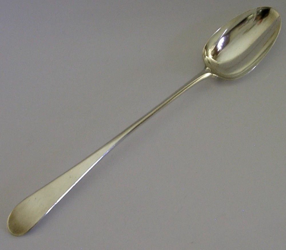 An 18th-century Georgian sterling silver basting spoon featuring a long, tapered stem and a polished oval bowl.