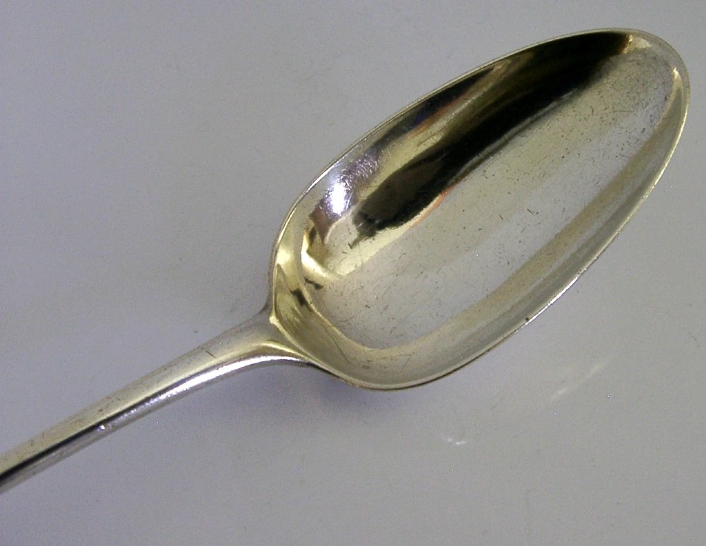 An 18th-century Georgian sterling silver basting spoon featuring a long, tapered stem and a polished oval bowl. View III