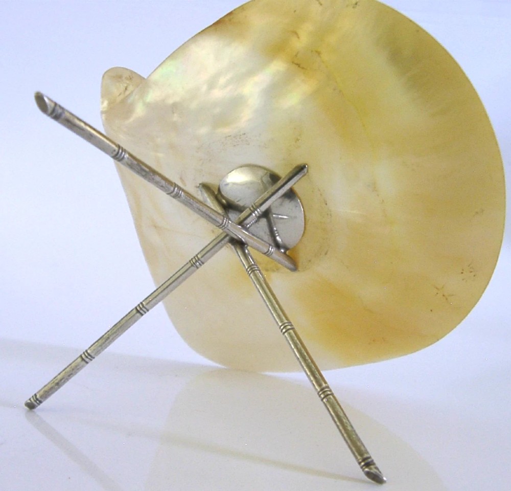 A shallow mother of pearl shell dish supported by a crossed sterling silver tripod stand designed in a bamboo motif. View II