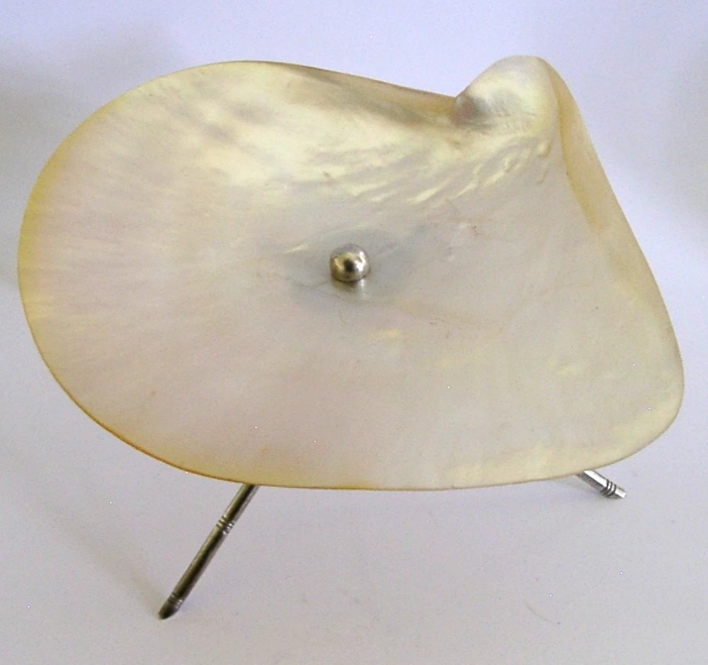 A shallow mother of pearl shell dish supported by a crossed sterling silver tripod stand designed in a bamboo motif. View III