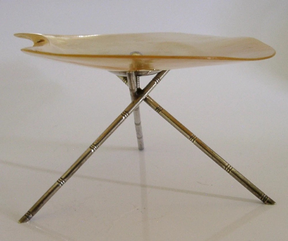 A shallow mother of pearl shell dish supported by a crossed sterling silver tripod stand designed in a bamboo motif. View IV