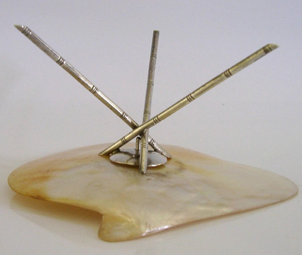 A shallow mother of pearl shell dish supported by a crossed sterling silver tripod stand designed in a bamboo motif. View VI