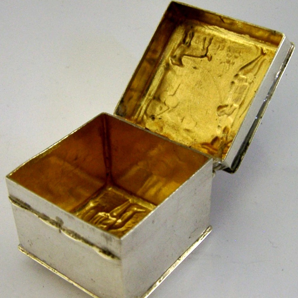 A small rectangular sterling silver box with a hinged lid featuring a raised relief scene of a figure walking a dog near a rustic building. View III
