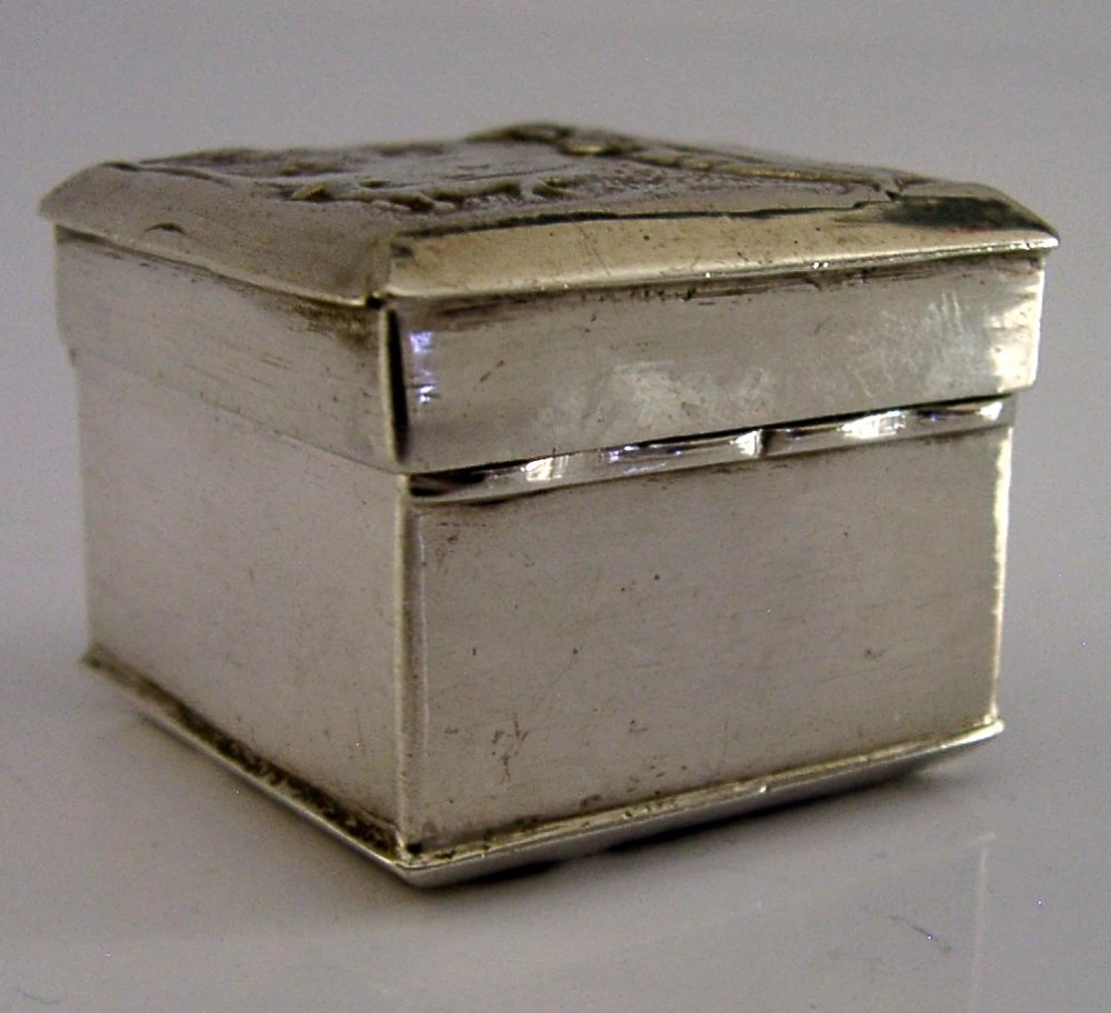 A small rectangular sterling silver box with a hinged lid featuring a raised relief scene of a figure walking a dog near a rustic building. View VI