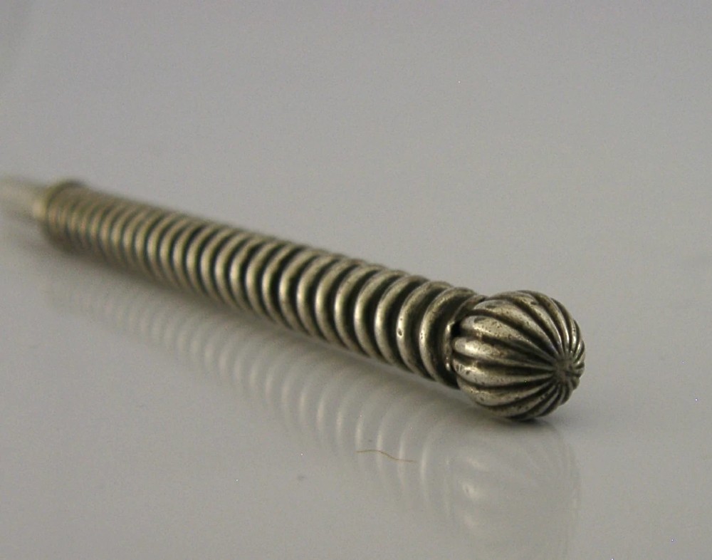 A Victorian sterling silver propelling pencil featuring a ribbed barrel design and a rounded fluted finial. View V