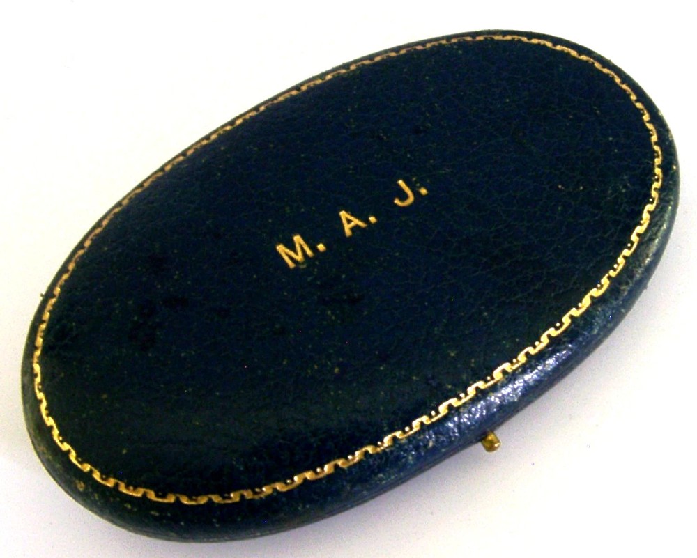 An opened oval fitted leather case displaying an Edwardian sterling silver sewing kit with scissors, thimble, bodkin, and needle case. View VI