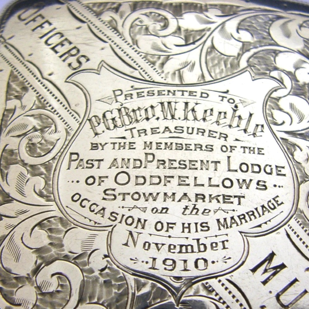 An engraved Edwardian sterling silver cigarette case featuring floral foliage and presentation text for the Independent Order of Oddfellows dated November 1910. View II