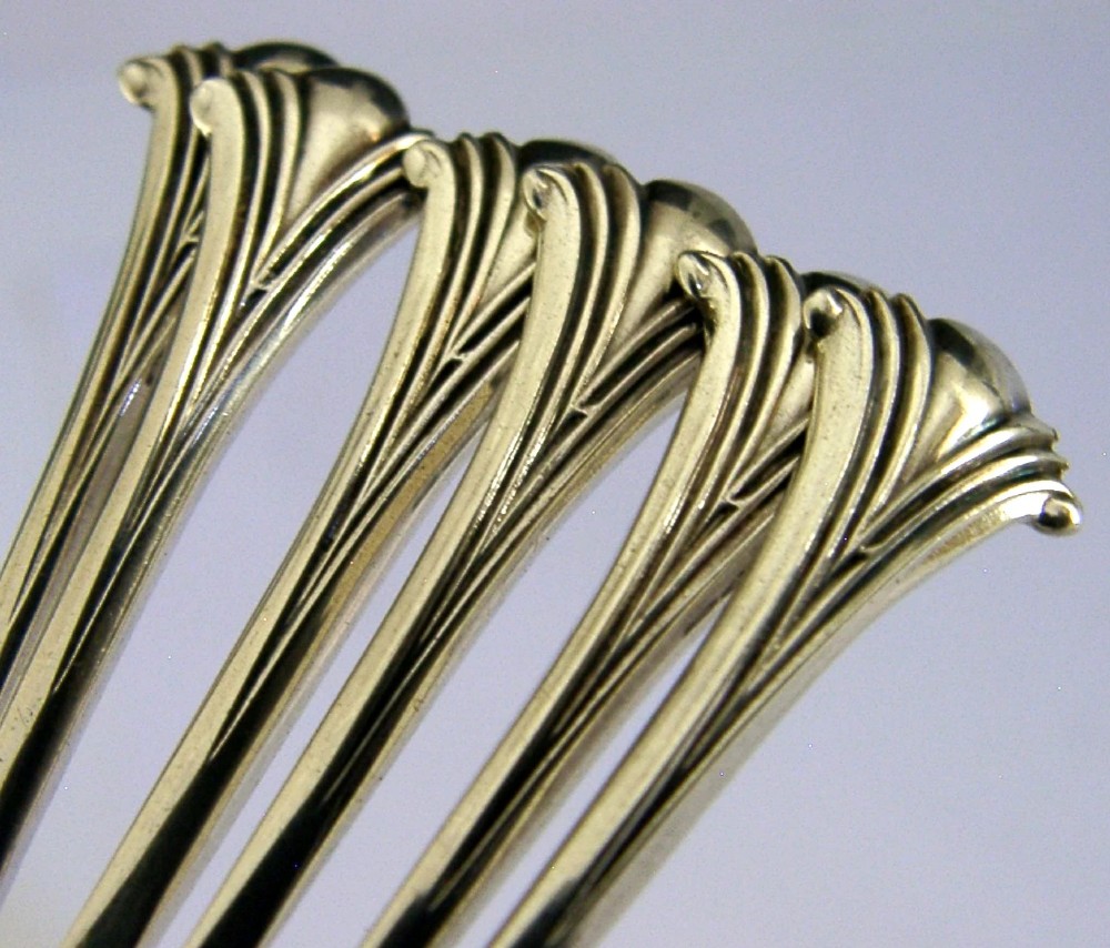 A set of six sterling silver teaspoons featuring twisted stems and shell motif terminals displayed on a light surface. View II