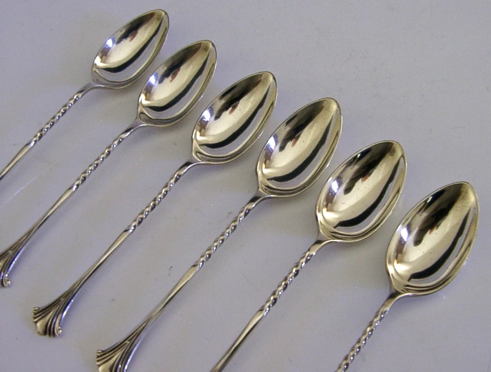 A set of six sterling silver teaspoons featuring twisted stems and shell motif terminals displayed on a light surface. View III