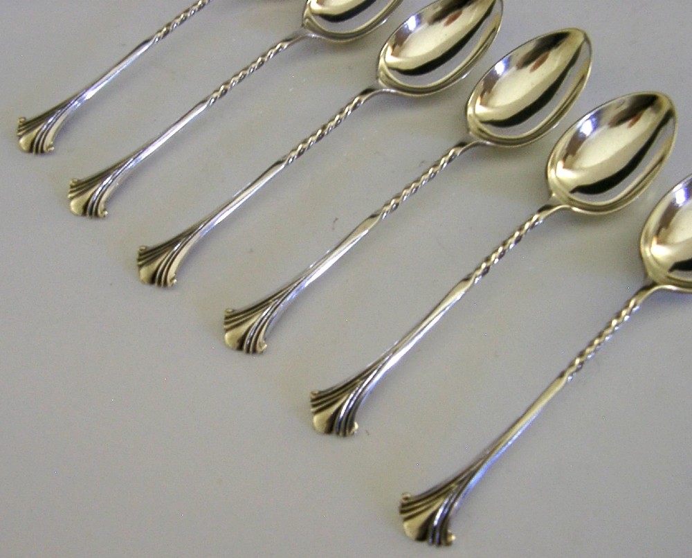 A set of six sterling silver teaspoons featuring twisted stems and shell motif terminals displayed on a light surface. View IV