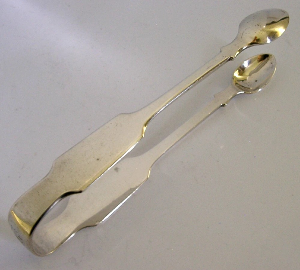A pair of Victorian sterling silver sugar tongs featuring a classic Fiddle pattern handle and spoon-shaped grips.