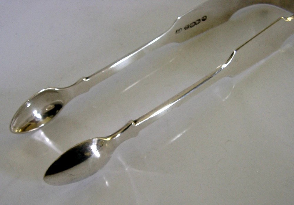 A pair of Victorian sterling silver sugar tongs featuring a classic Fiddle pattern handle and spoon-shaped grips. View IV