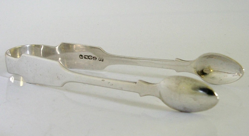 A pair of Victorian sterling silver sugar tongs featuring a classic Fiddle pattern handle and spoon-shaped grips. View VII