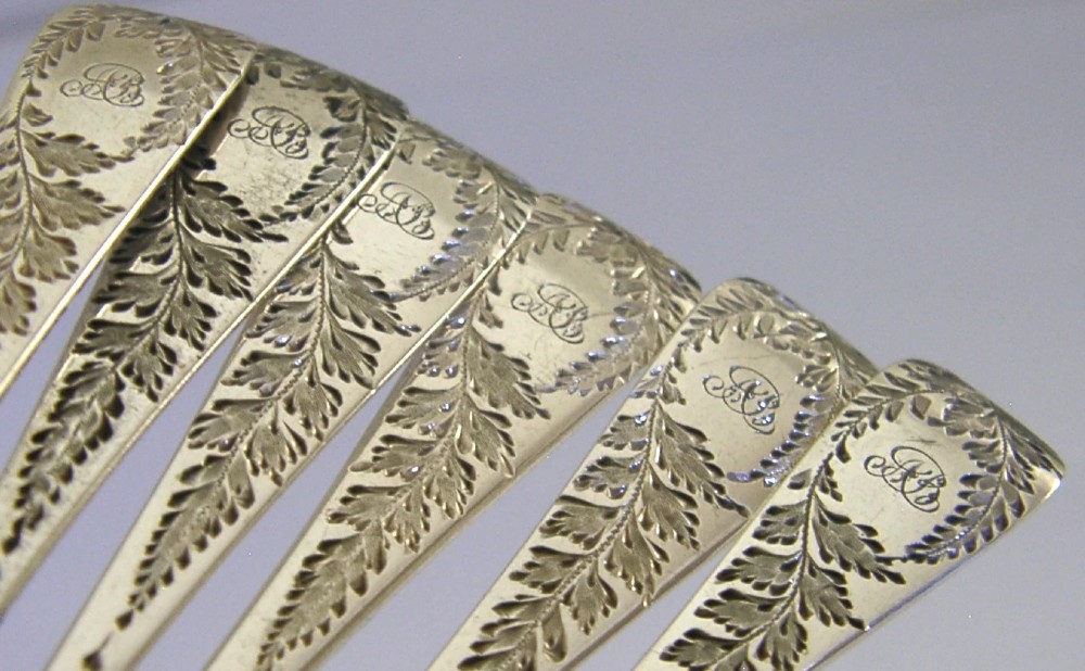 A set of six engraved Victorian sterling silver spoons arranged inside a black fitted presentation case lined with deep purple velvet. View III