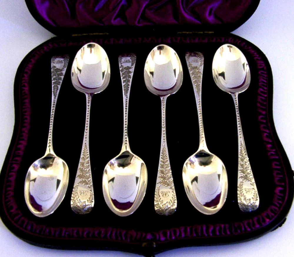 A set of six engraved Victorian sterling silver spoons arranged inside a black fitted presentation case lined with deep purple velvet. View IV