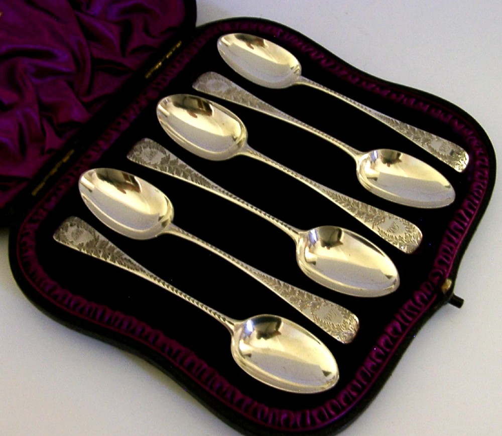 A set of six engraved Victorian sterling silver spoons arranged inside a black fitted presentation case lined with deep purple velvet. View VI