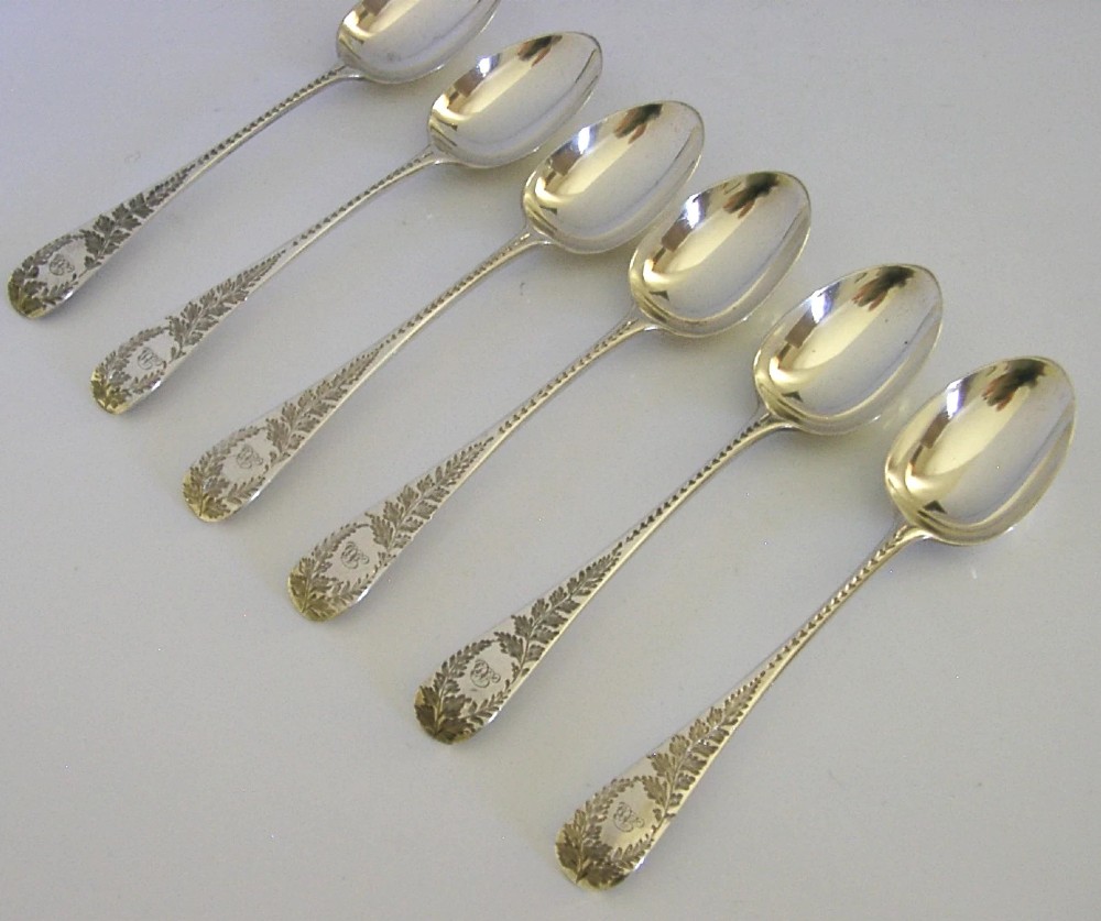 A set of six engraved Victorian sterling silver spoons arranged inside a black fitted presentation case lined with deep purple velvet. View IX