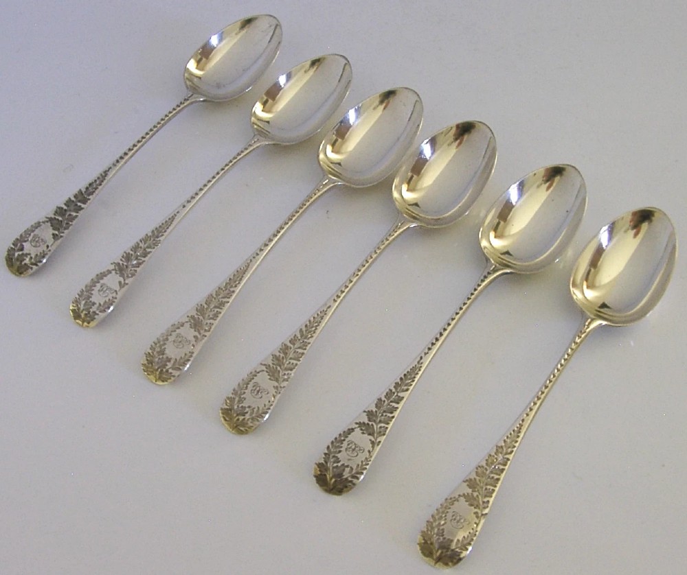 A set of six engraved Victorian sterling silver spoons arranged inside a black fitted presentation case lined with deep purple velvet. View X
