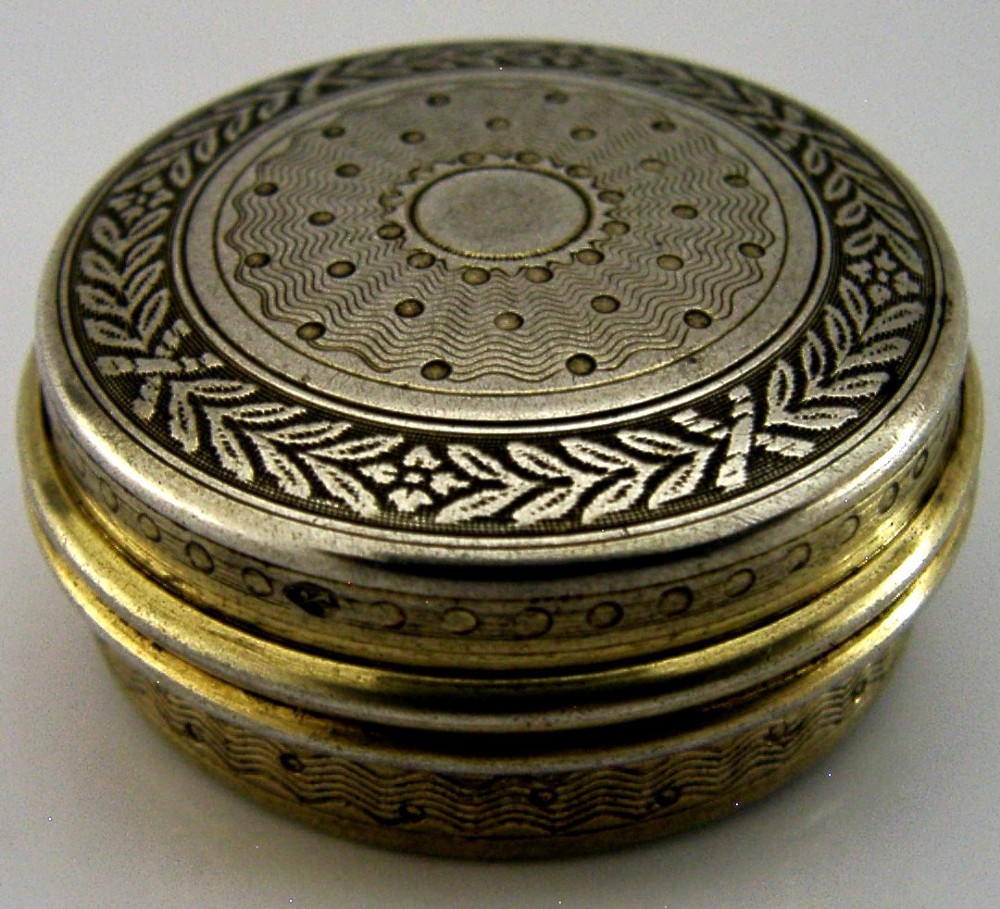 A circular French sterling silver gilt trinket box featuring engine-turned guilloche detailing and a decorative laurel leaf border. View IV